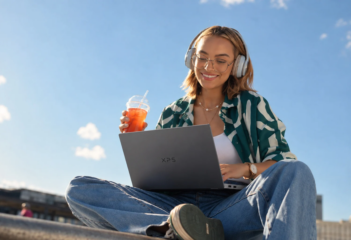 Studente werkt buiten op een laptop met een koptelefoon op